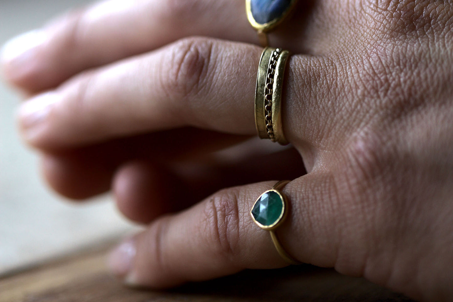Handcrafted Emerald pinky ring next to solid gold ring stack