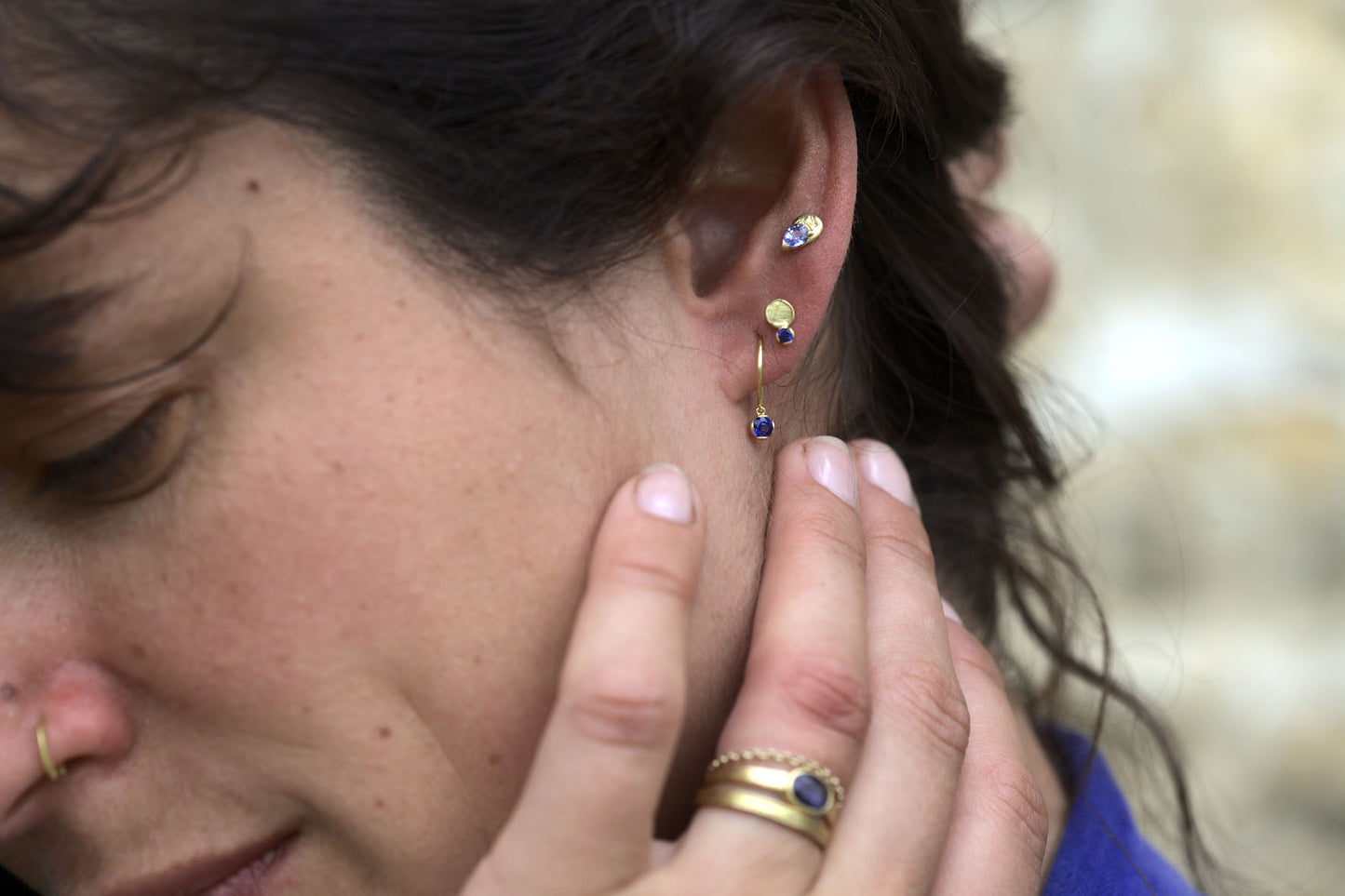 Model wearing recycled gold, handcrafted blue sapphire earrings and rings.